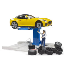 Yellow toy roadster on lift at car service center with mechanic figure and tires around.