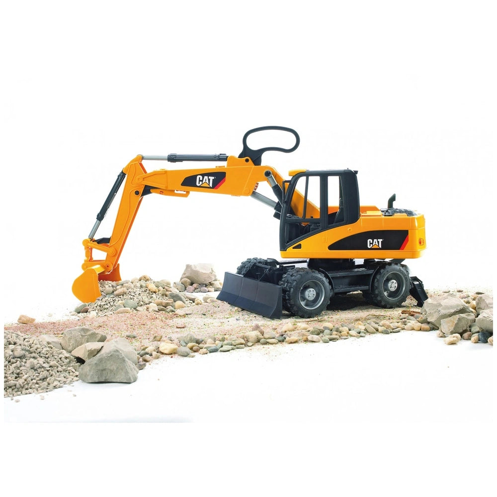 Yellow Bruder CAT Wheel Excavator toy on rocky terrain with articulated arm and detailed features.