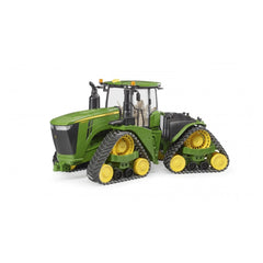 Green and yellow Bruder John Deere 9620RX toy tractor with track belts, detailed cabin, and movable parts.