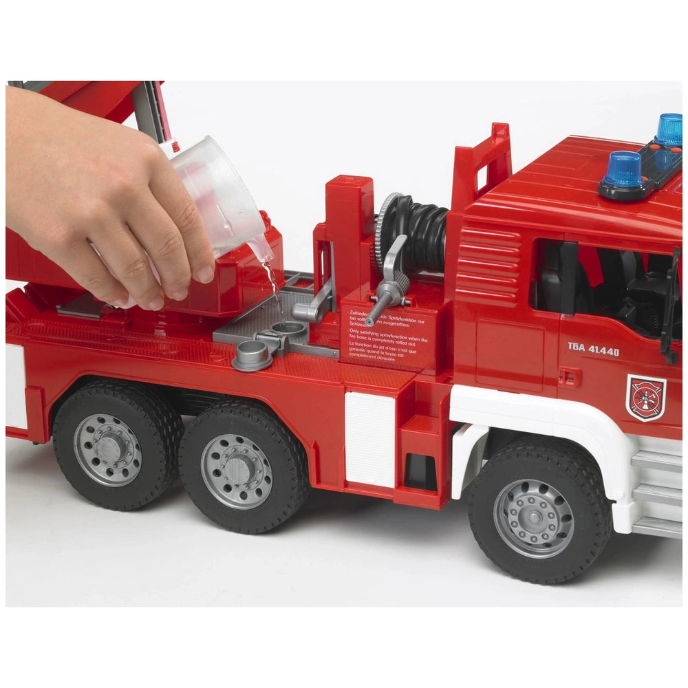 Hand pouring water into red Bruder MAN TGA fire engine toy's tank, featuring hose and ladder, on white background.