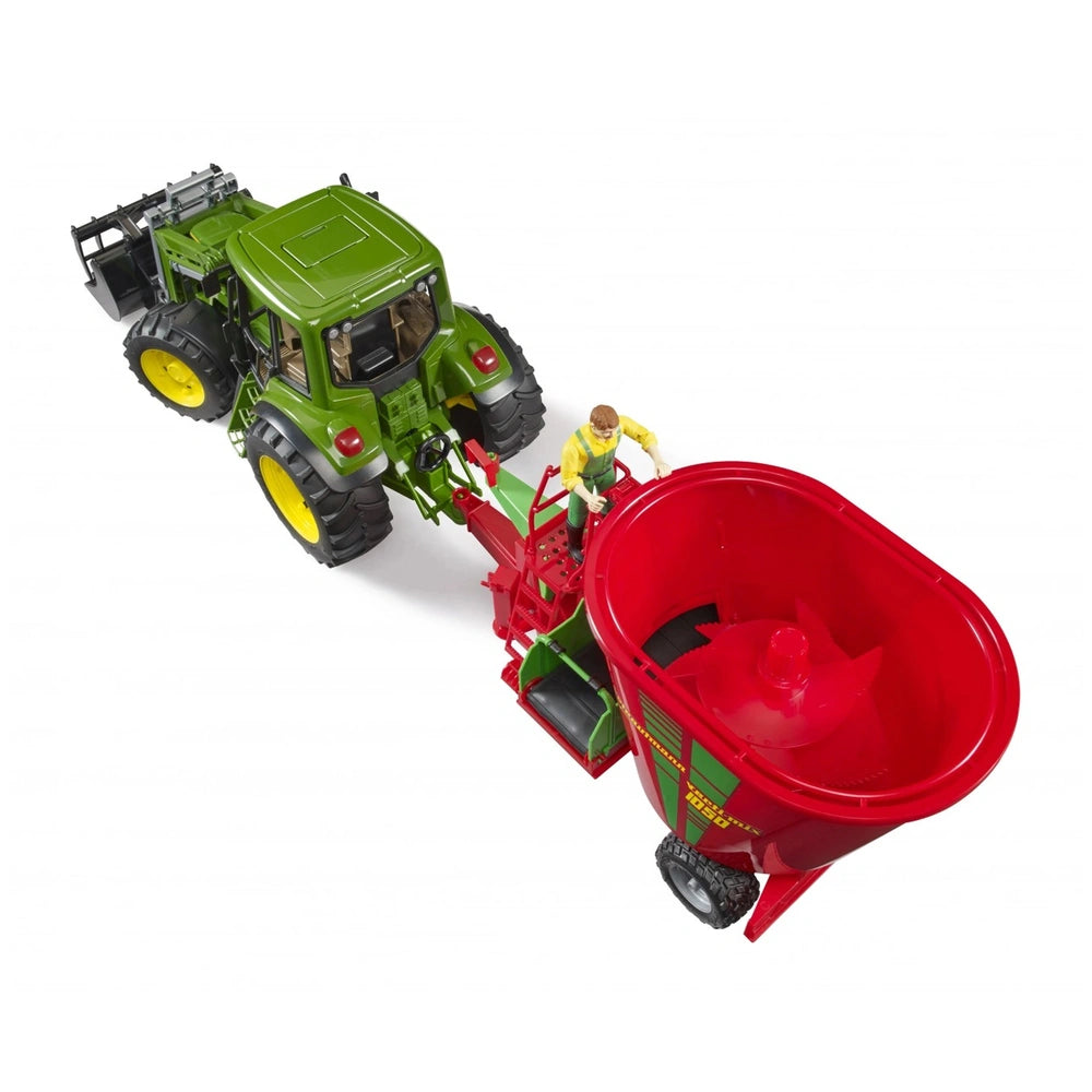 Toy tractor with green body and yellow wheels pulling a red fodder mixer, includes a farmer figurine.