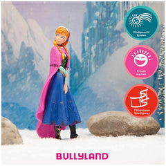 Bullyland Disney Anna toy figure in blue dress, pink cape, and black boots, set against a snowy landscape background.