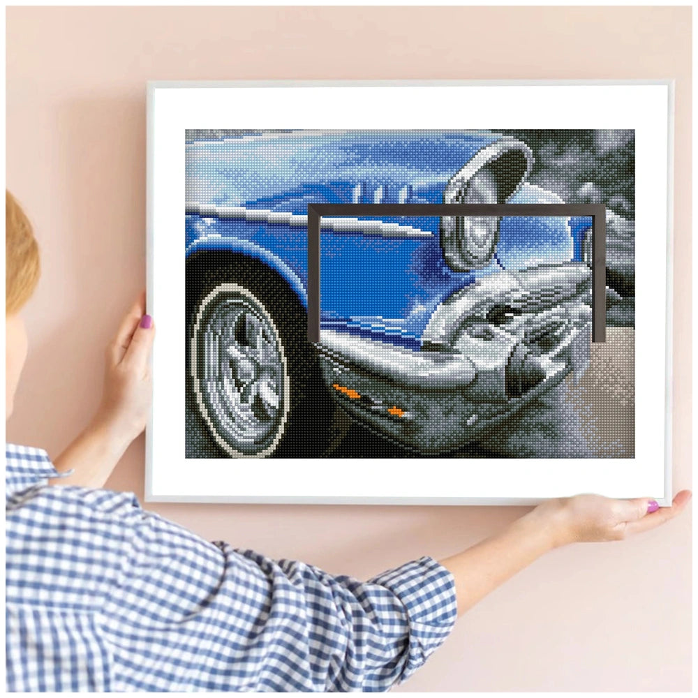 Diamond Dotz 50s Classic displayed in a black frame on a light pink wall, held by a person in a plaid shirt with painted nail
