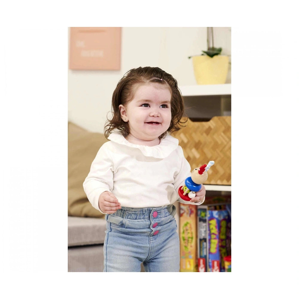 Eichhorn Baby Wooden Rattle Rabbit is held by a smiling child in a cozy indoor setting, showcasing its colorful design.