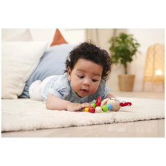 Eichhorn Baby Wooden Teething Ring Rabbit is engaged with a colorful toy on a fluffy white rug.
