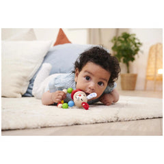 Eichhorn baby wooden teething ring rabbit is held by a young child lying on a soft surface, engaging directly with the camera