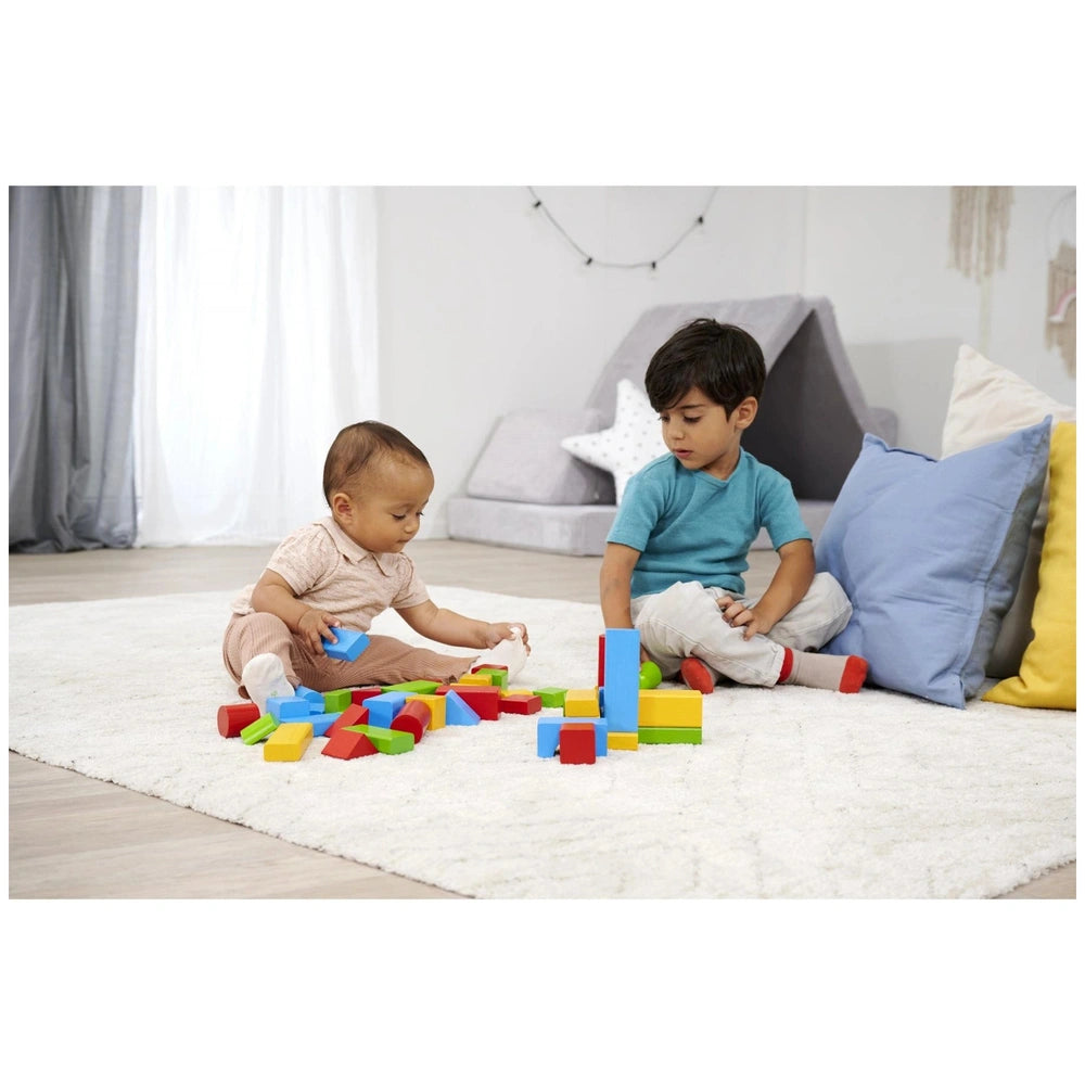 Eichhorn colored wooden blocks are being used by two children on a light carpet in a bright indoor playroom setting.