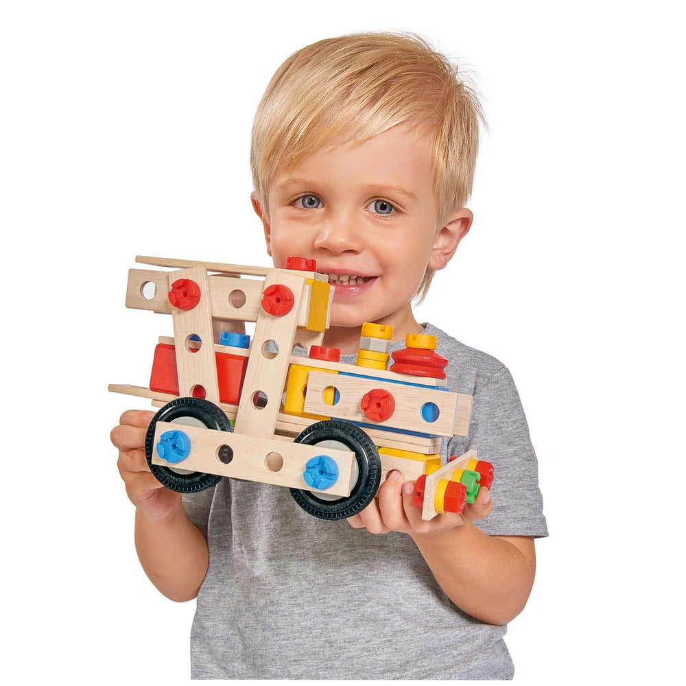 Eichhorn Constructor 4 in 1 construction set held by a smiling child with blonde hair, featuring colorful wooden and plastic