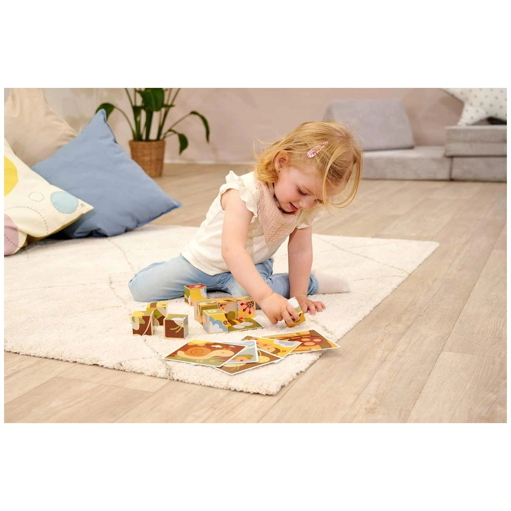 Eichhorn colorful puzzle blocks are scattered around a young girl playing on a white rug over a wooden floor.
