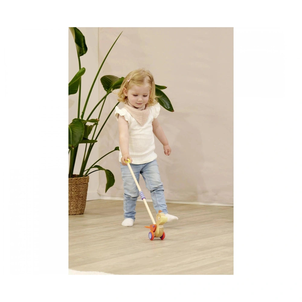 Eichhorn Duck push toy with a young child in a white top and blue jeans interacting on a wooden floor.