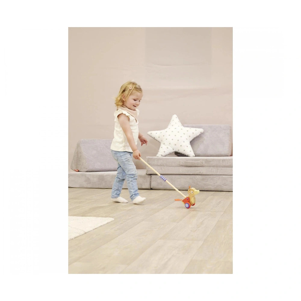 Eichhorn duck push toy being held by a child in casual attire, set in a cozy living room environment.