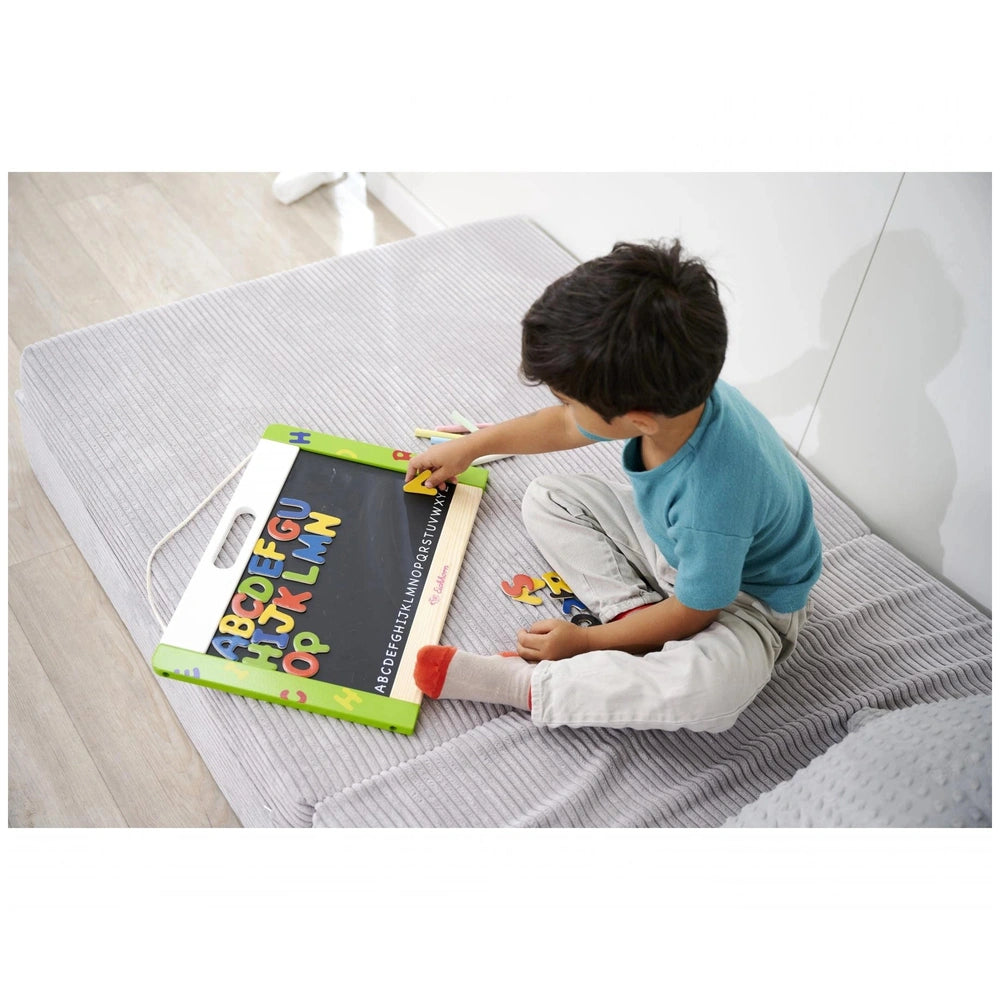 Eichhorn Magnetic and Chalkboard, a child engaging with a colorful magnetic board on a gray mat in a cozy home setting.