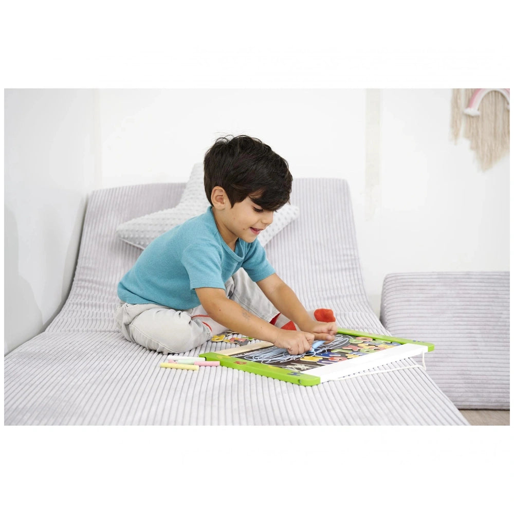 Eichhorn magnetic and chalkboard educational toys being used by a child sitting on a bed in a cozy, minimalist bedroom.