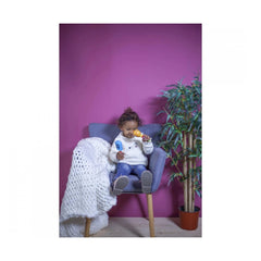 Eichhorn maracas held by a child in a cozy setting with a blue armchair and a purple wall.