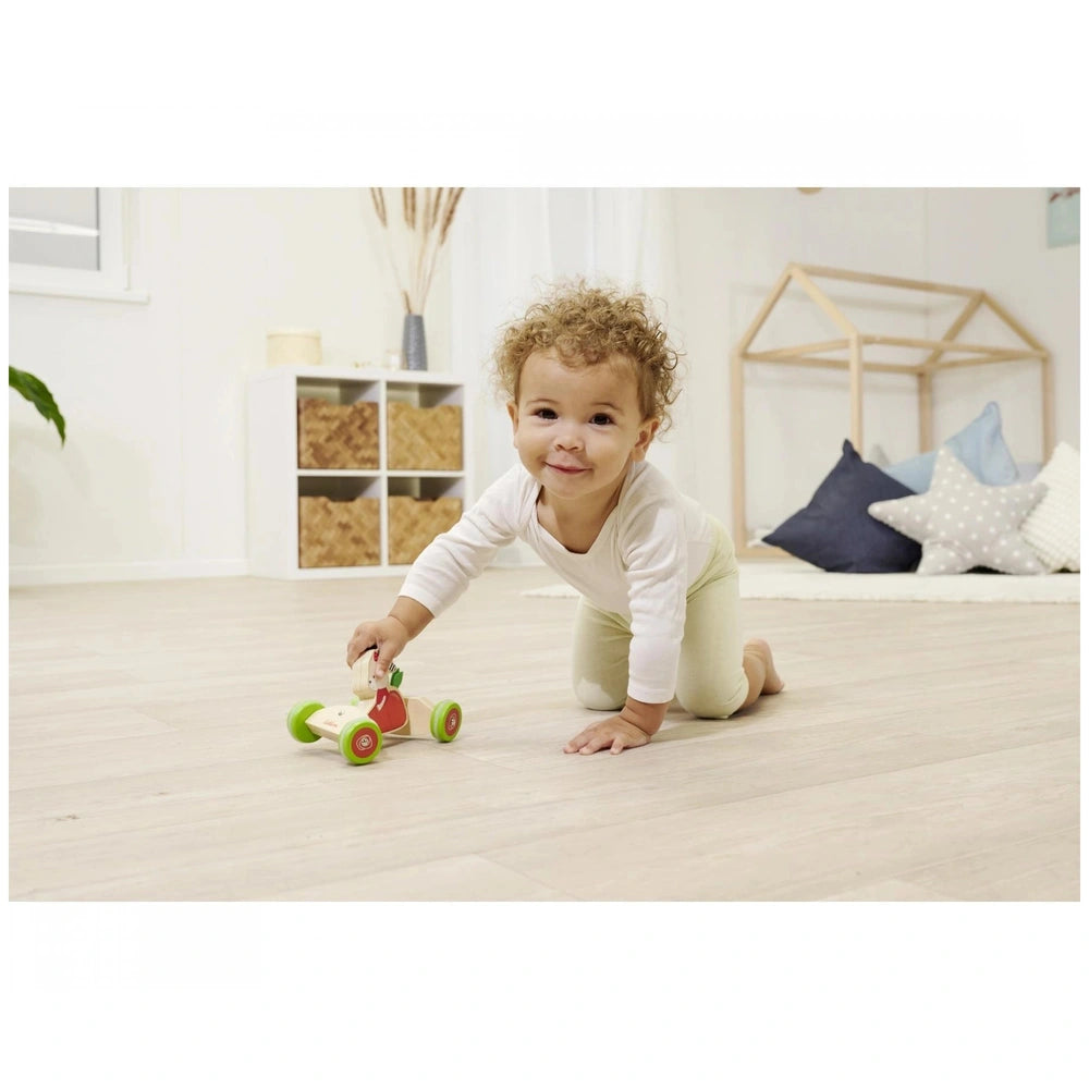 Eichhorn Push Vehicle toy with a toddler, showcasing colorful design in a modern, airy indoor playroom.