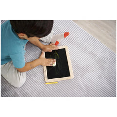 Eichhorn small blackboard with child drawing on tablet, surrounded by educational toys in a cozy indoor setting.