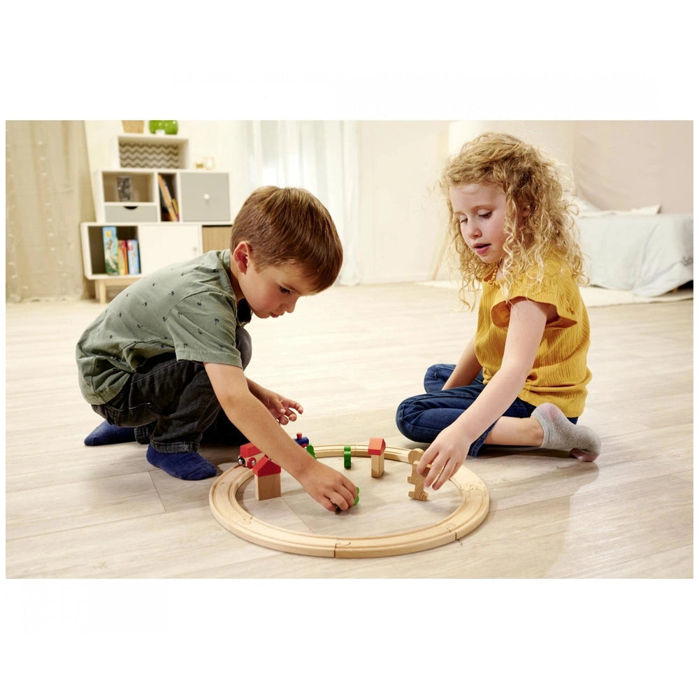 Eichhorn Train Track Playset with children playing, featuring wooden tracks and a train in a cozy indoor play area.