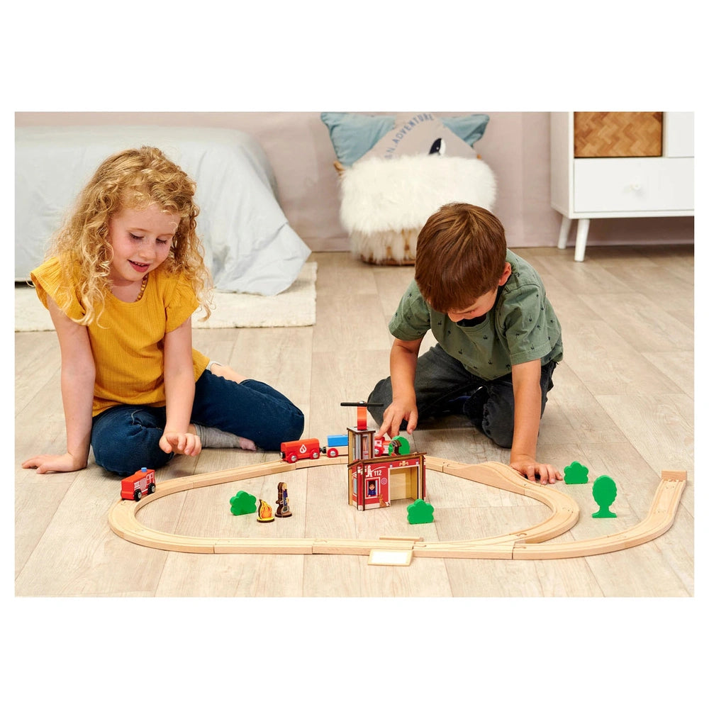 Eichhorn Train Track Playset featuring children playing with wooden trains and a bridge in a cozy indoor setting.