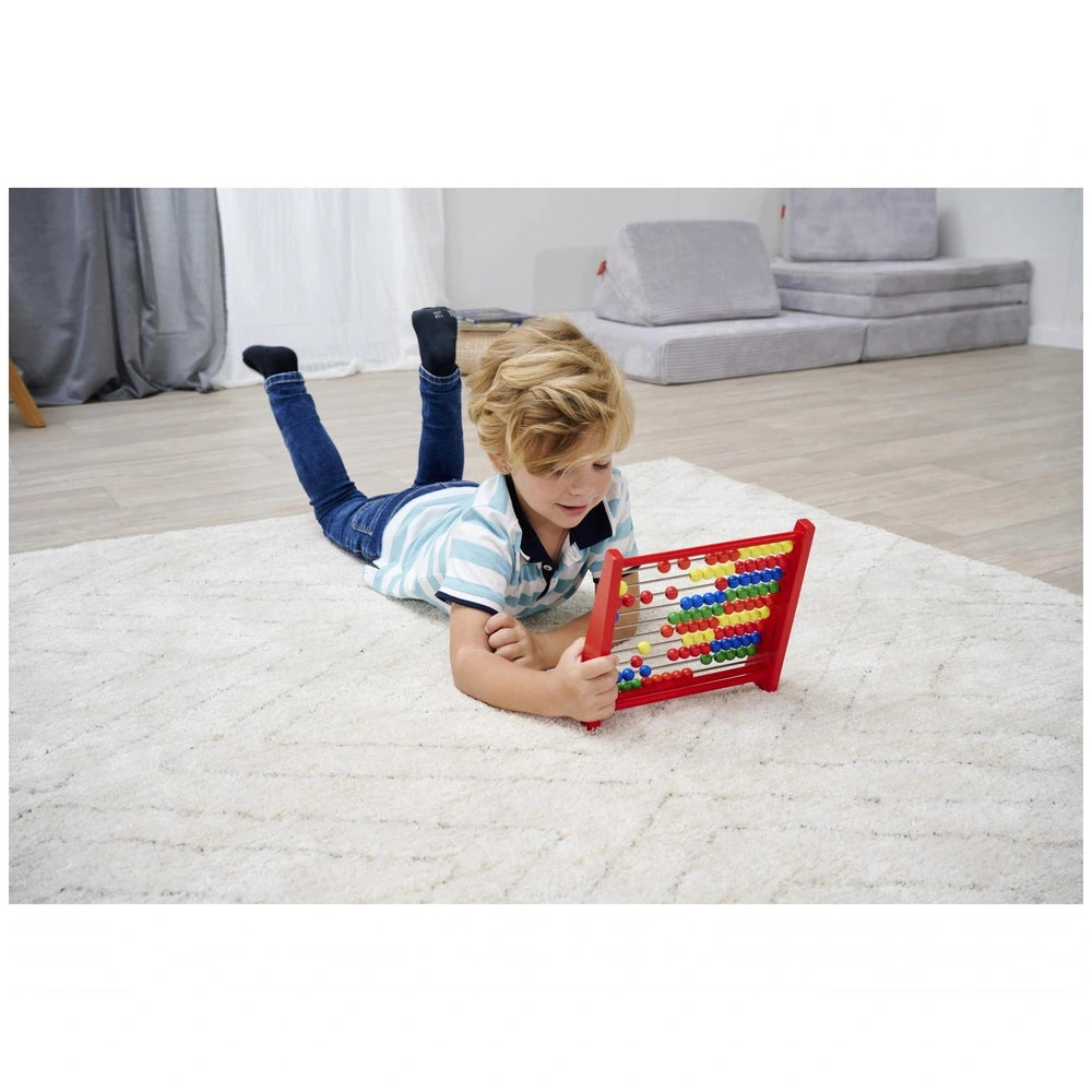 Eichhorn Wooden Slide Rule on carpeted floor, young boy with blonde hair engaging with colorful red abacus and learning toys.