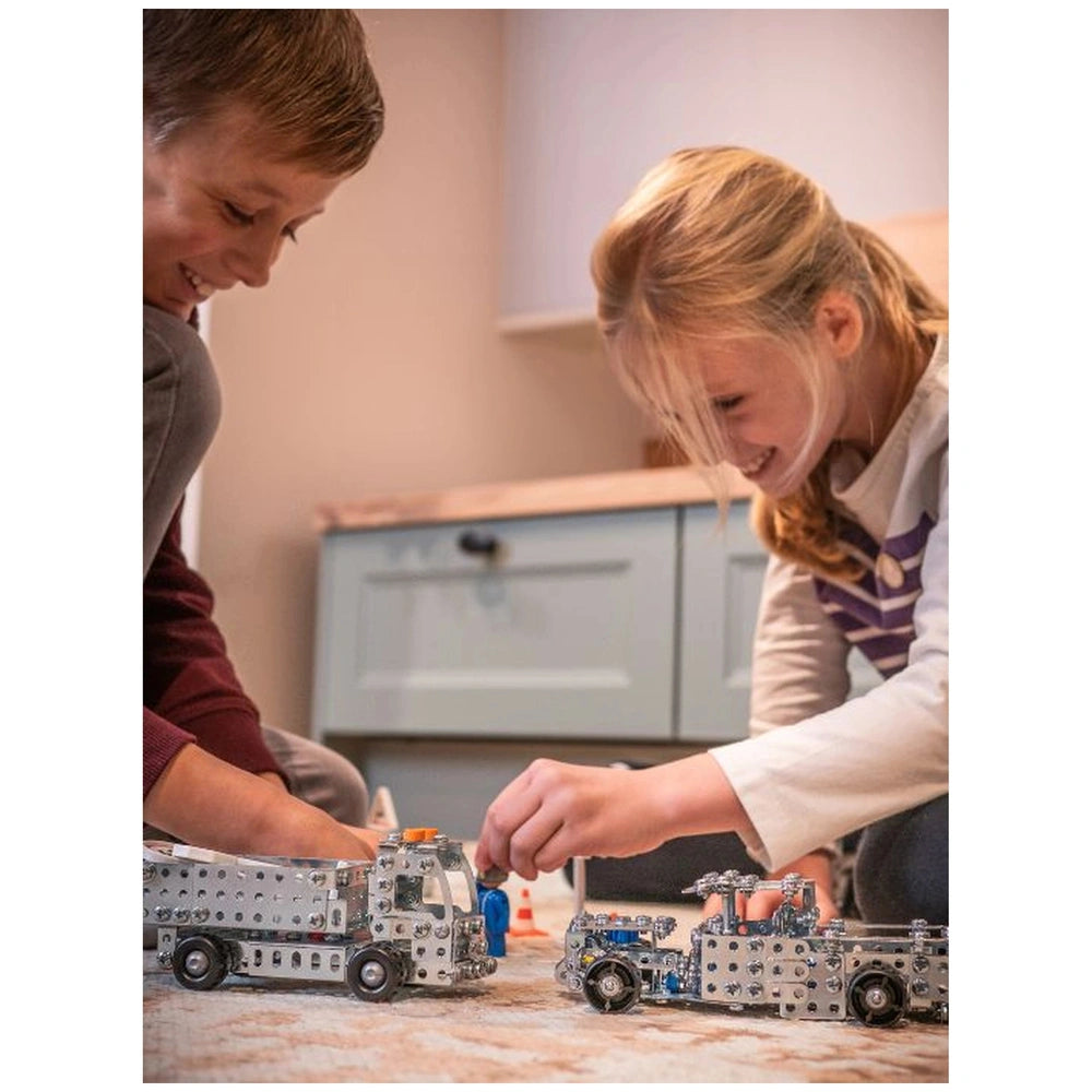 Eitech Crane Mini construction set with two children playing with metal and plastic toy trucks on a patterned carpet.