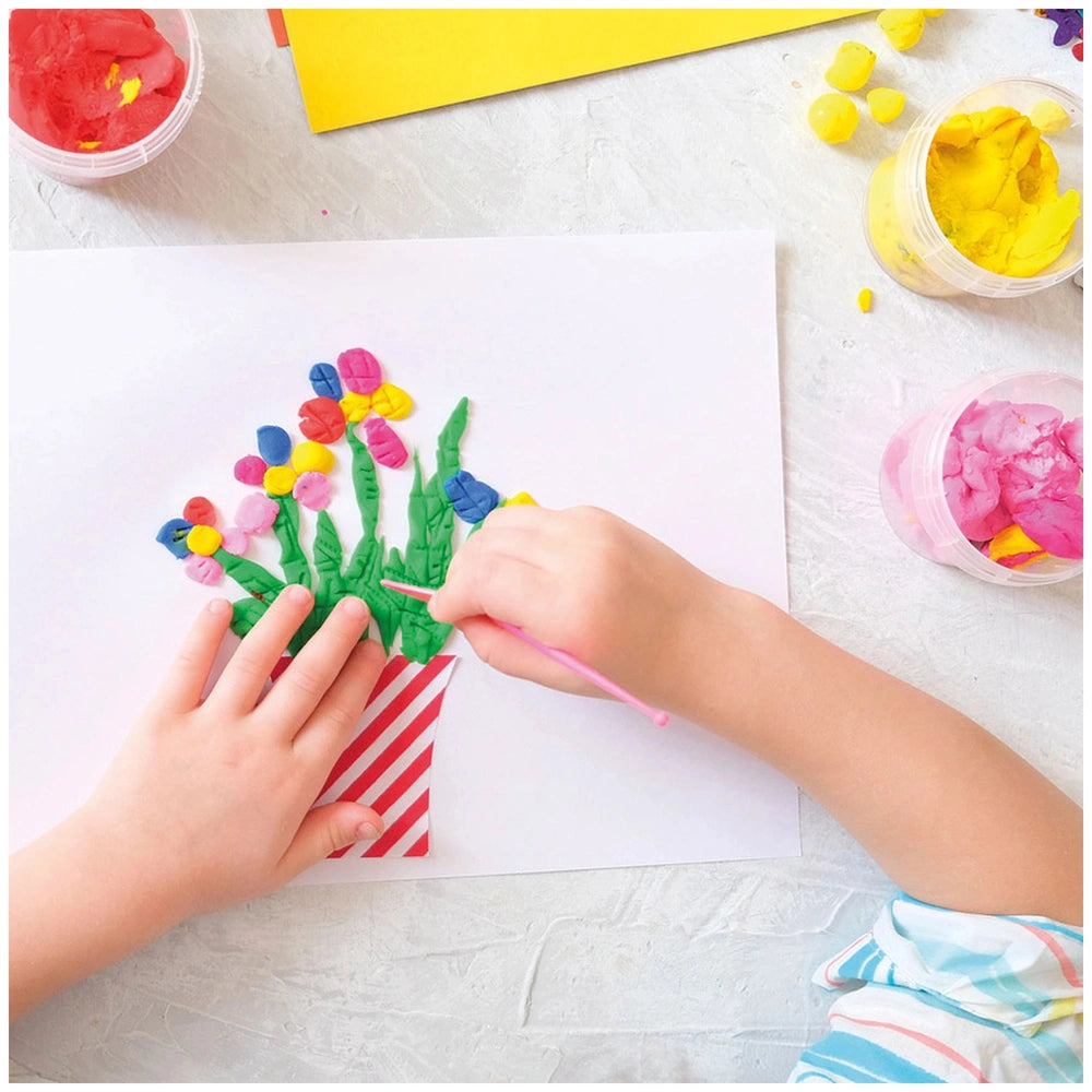 Feuchtmann clay pack displayed with a child's hand holding a red and white striped craft project adorned with colorful materi