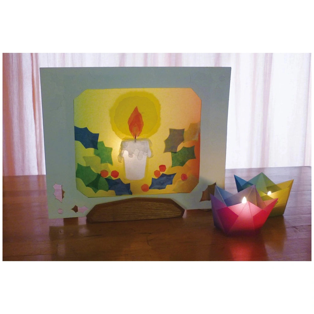 Folia transparent paper block featuring multi-coloured sheets on a wooden table with a lit pink candle in a holder.