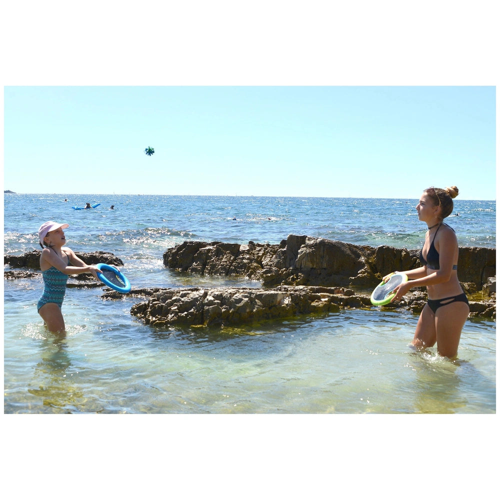 Gowi Active Hand Trampoline Game features two girls playing with blue and white plastic frisbees on a sandy beach.