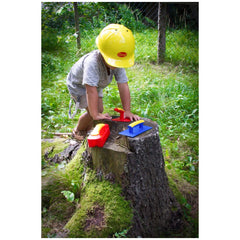 Gowi Design Bricklaying Set features a person in a yellow hard hat holding a red and yellow tool near a mossy stump and wire 