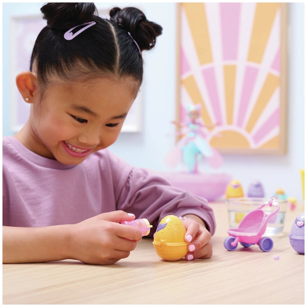 Hatchimals Alive Hatch N’ Stroll Playset is featured alongside a smiling girl playing with colorful toys on a wooden table.