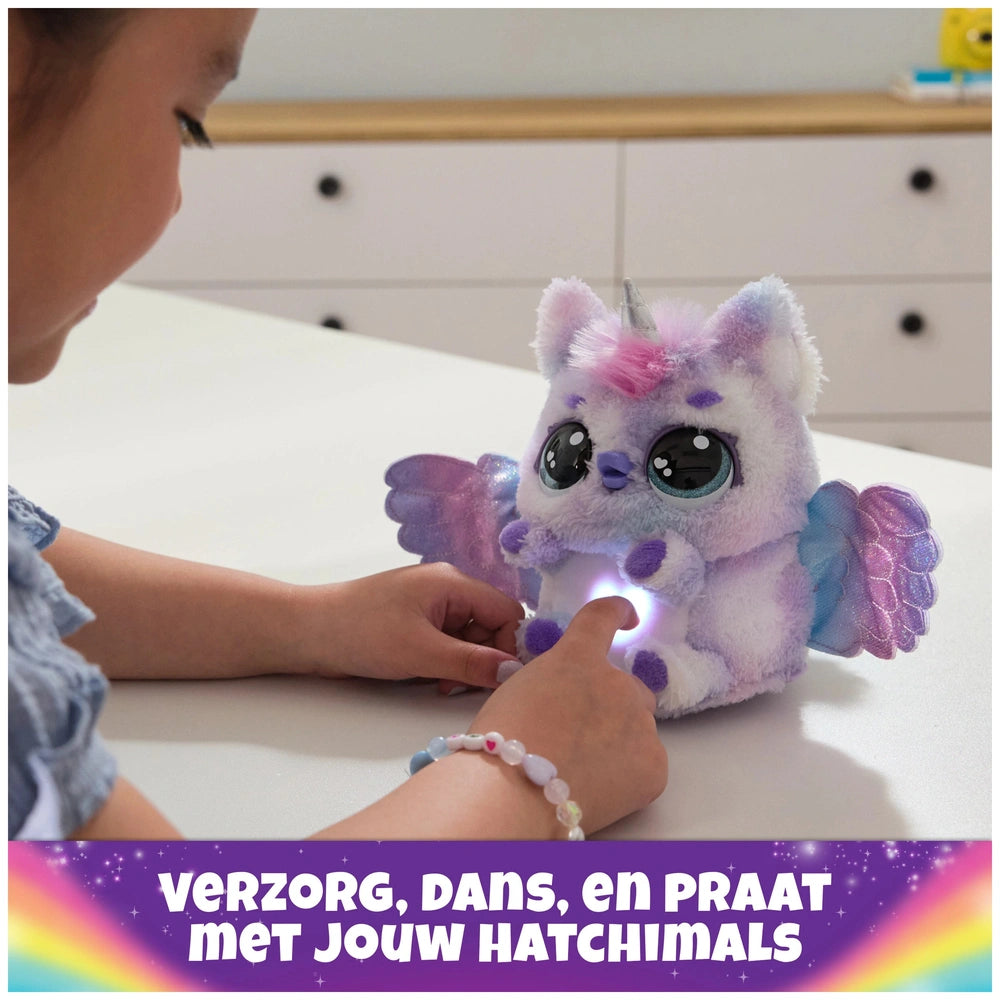 Hatchimals Alive Mystery Hatch Pufficorn plush toy in purple and blue held by a child, glowing softly on a white tabletop.