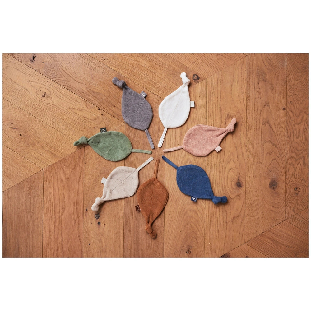 Jollein pacifier cloth featuring green, gray, pink, brown, and blue stuffed animals arranged on wooden flooring.