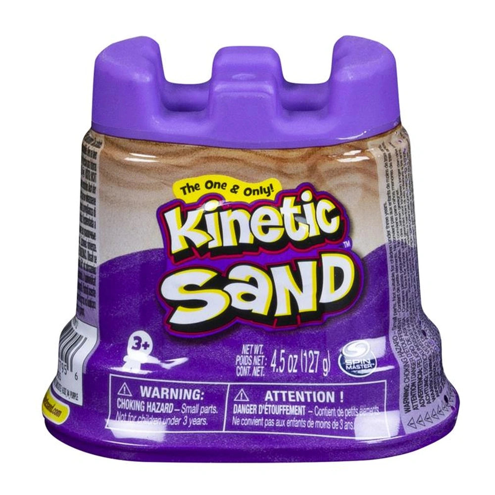 Kinetic Sand container with a purple lid, featuring a brownish-orange label and warning symbol, stands upright on a plain bac