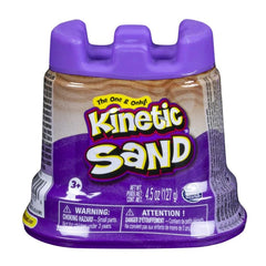 Kinetic Sand container with a purple lid, featuring a brownish-orange label and warning symbol, stands upright on a plain bac