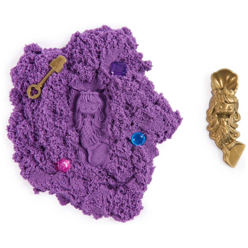 Kinetic Sand Mini Mermaid Lock features a golden key resting on a textured purple surface.
