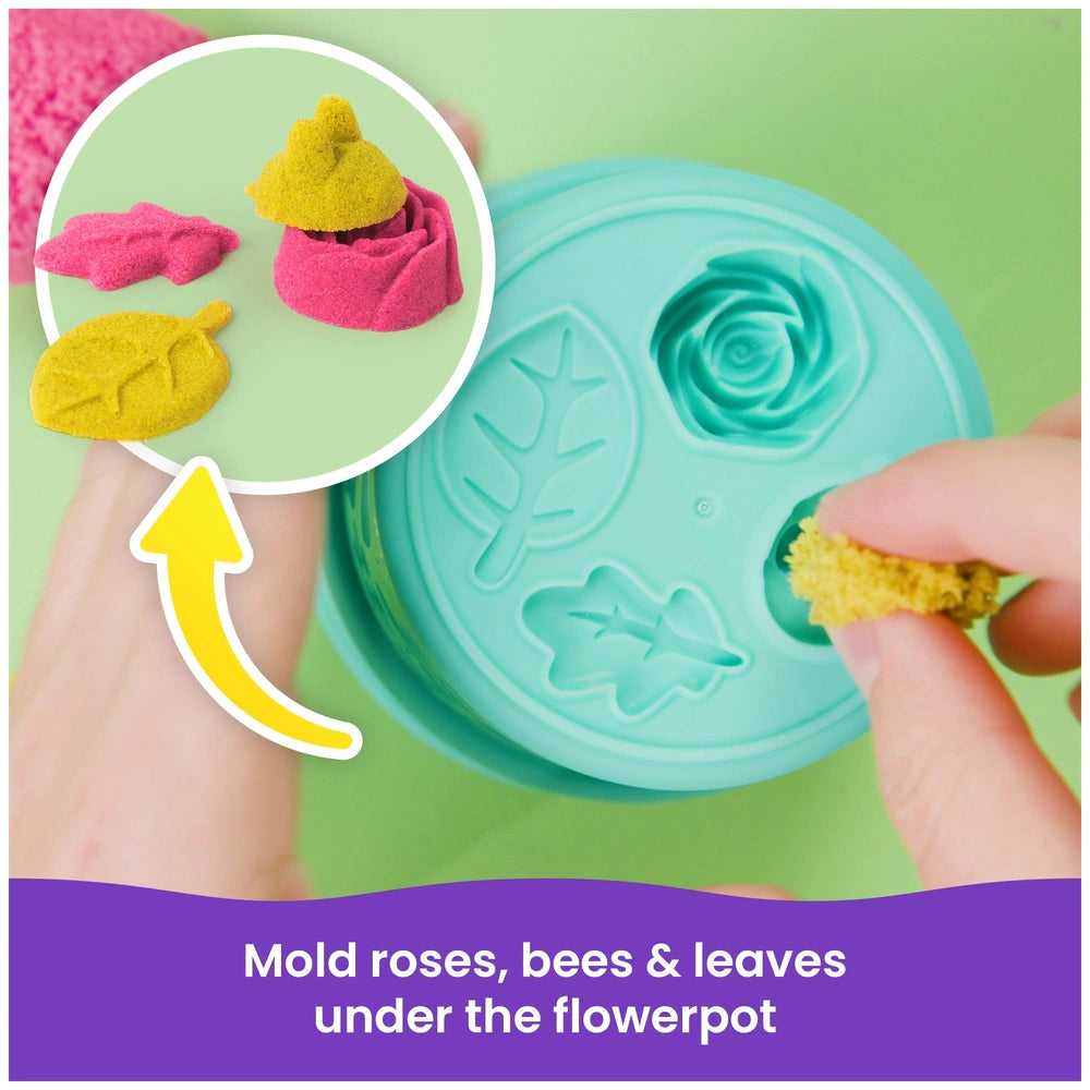 Kinetic Sand Squish Blossom features vibrant yellow, pink, and green rose petals arranged around a flowerpot with instruction
