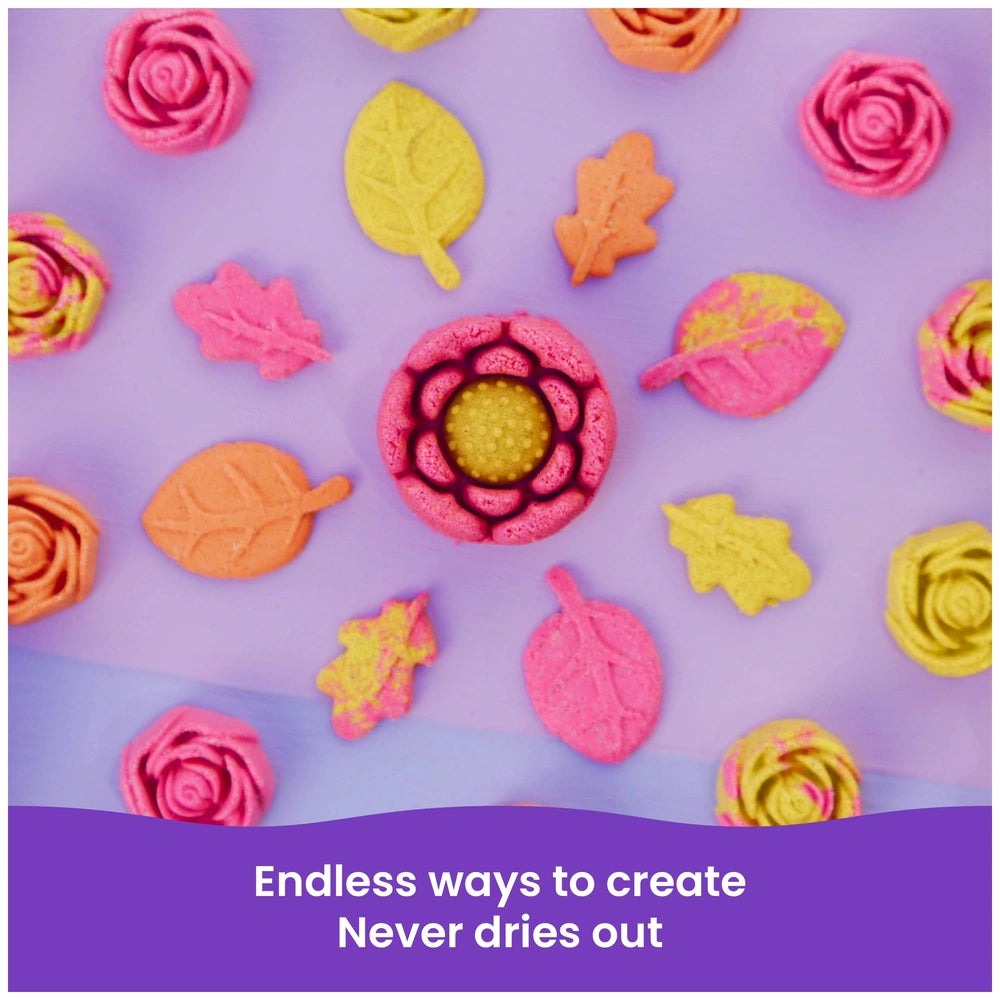 Kinetic Sand Squish Blossom features a pink flower, pink rose, and colorful leaves on a smooth surface.