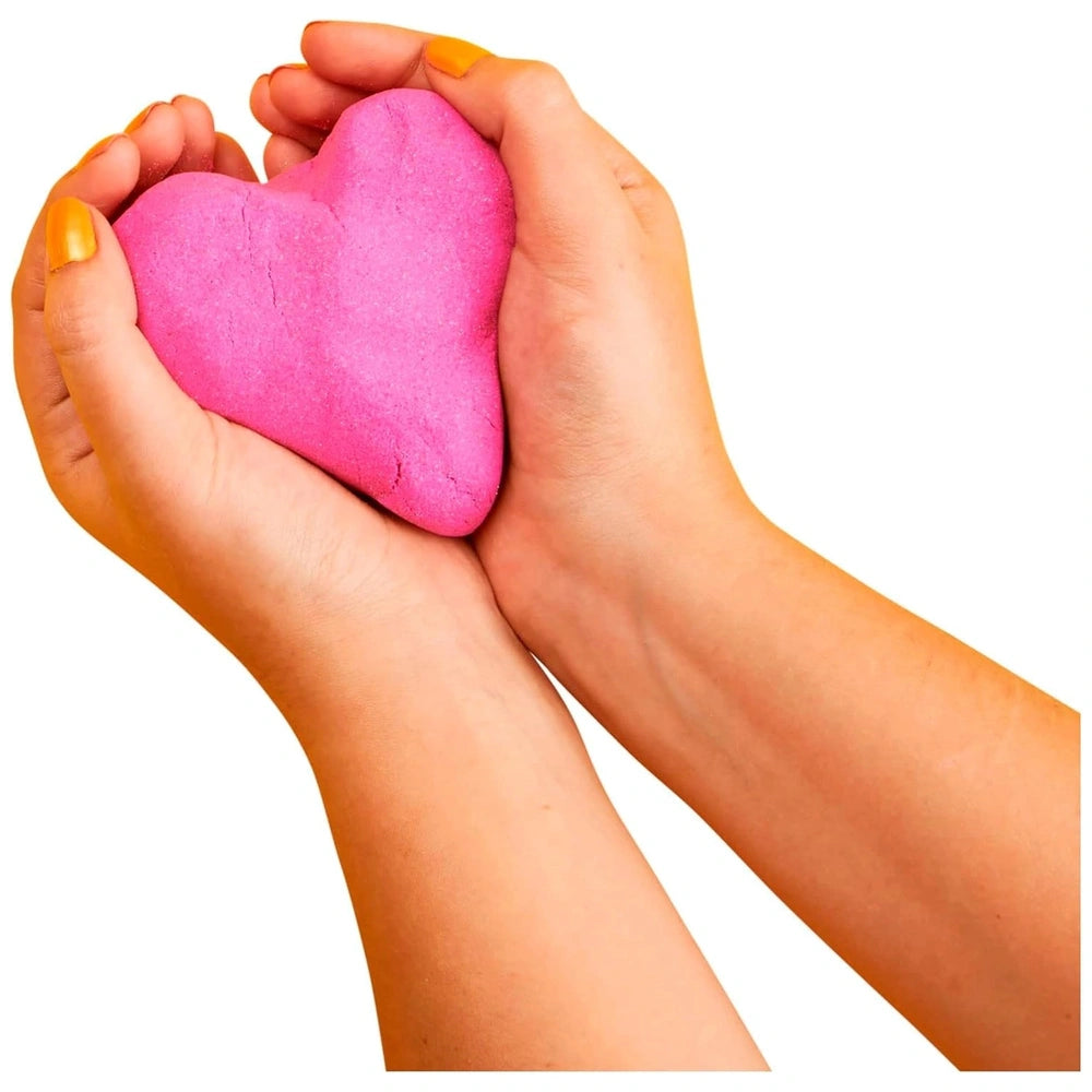Kinetic-Sand heart-shaped object held by hands, vibrant pink against a plain white background.