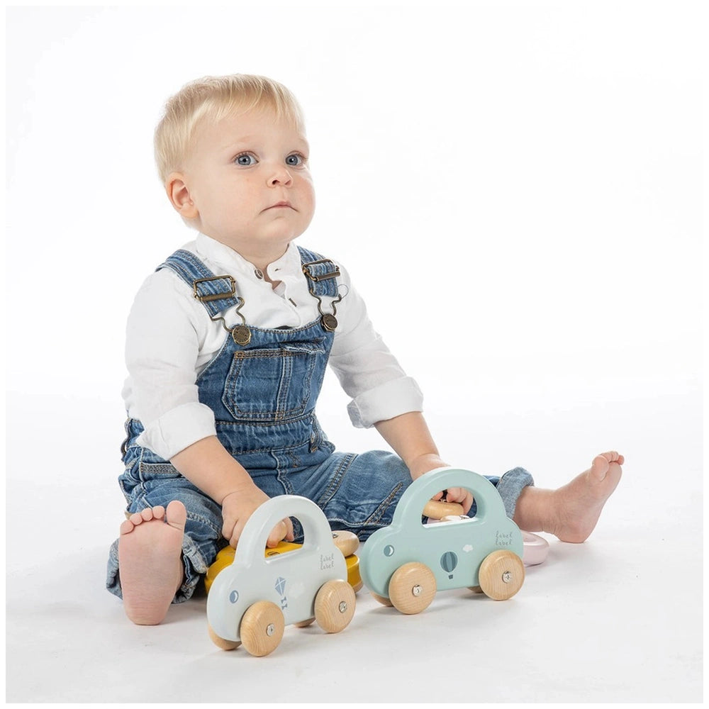 Label-Label Little Car push and pull toy with a young child in denim clothing, showcasing blue eyes and light skin.