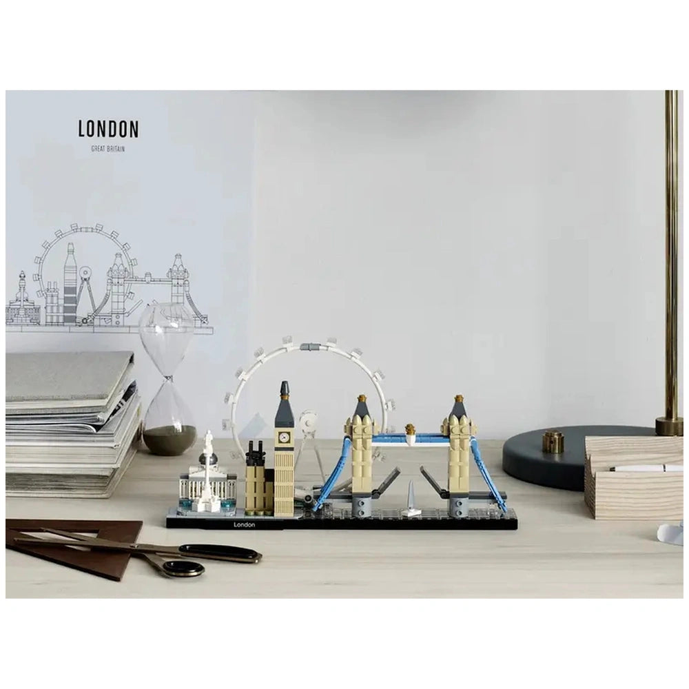 Lego Architecture London construction set displayed on a light wooden desk alongside a clock tower model, bridge, and books.