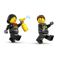 Two LEGO firefighter minifigures running joyfully, one holding a yellow toy extinguisher, both wearing black fire uniforms with vibrant details.