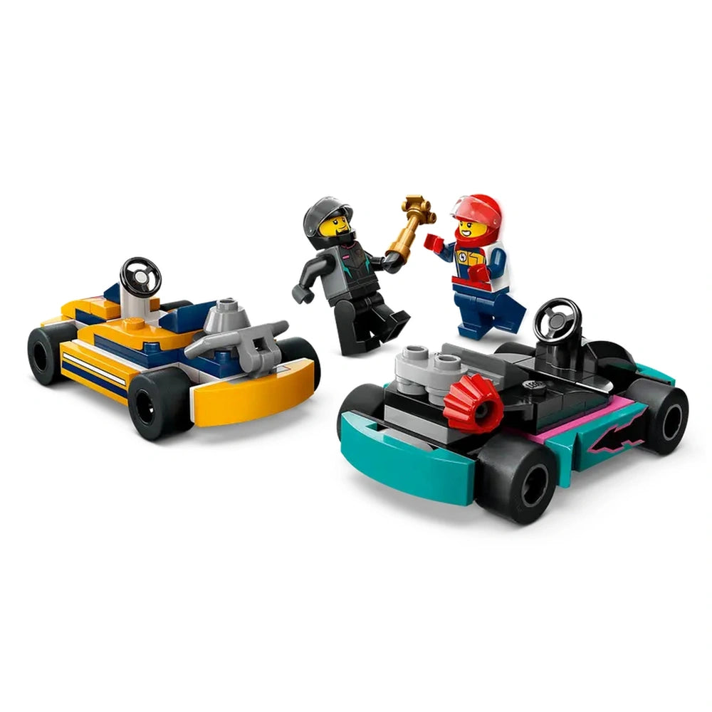 Two colorful LEGO go-karts, one orange and one turquoise, with two cheerful minifigures celebrating a race victory holding a trophy.
