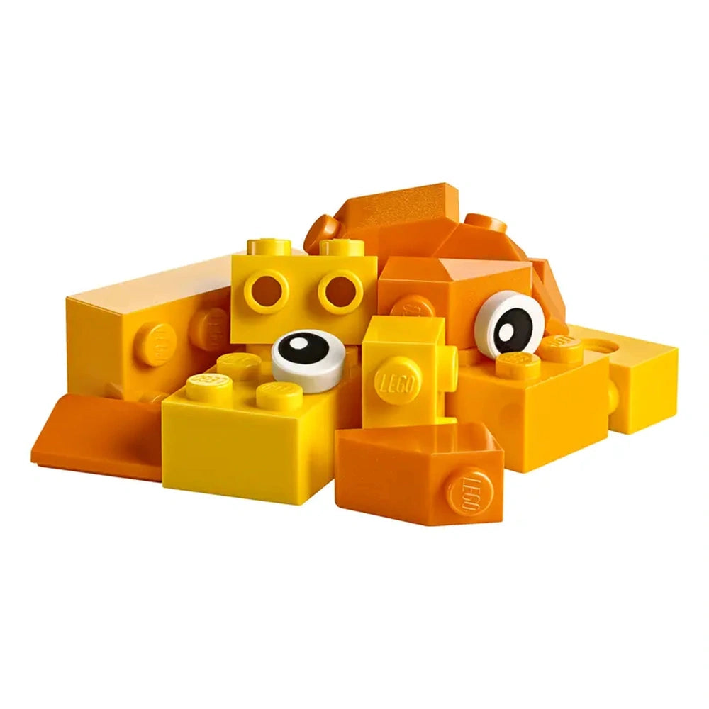A colorful pile of yellow and orange LEGO bricks, featuring various shapes and sizes, including pieces with eyes, suggesting imaginative play.