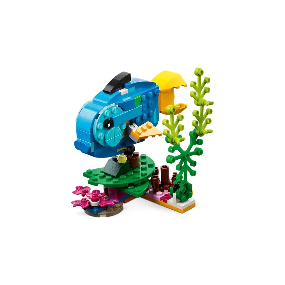 Colorful LEGO® construction set featuring a vibrant blue fish with orange accents, surrounded by green seaweed and pink coral on a base.