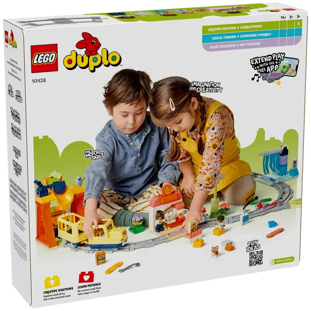 Two children playing with the Lego Duplo Big Interactive Community Train set, surrounded by colorful figures and a train station on a bright play mat.