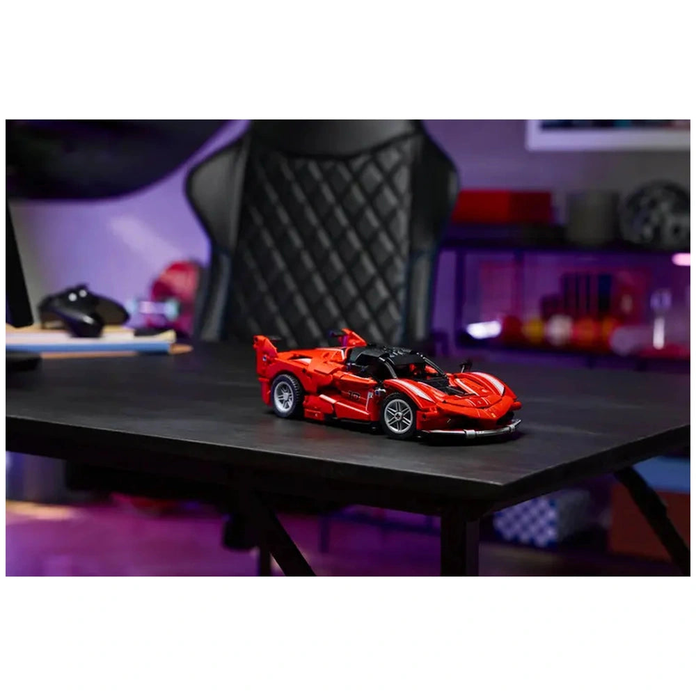 LEGO Ferrari FXX K model car kit in vibrant red, displayed on a sleek black table, with a modern gaming chair in the background.