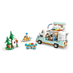 LEGO Friends camper van set featuring a cheerful camper, three minidolls, a bicycle, and forest scene with trees and a ferret figure.
