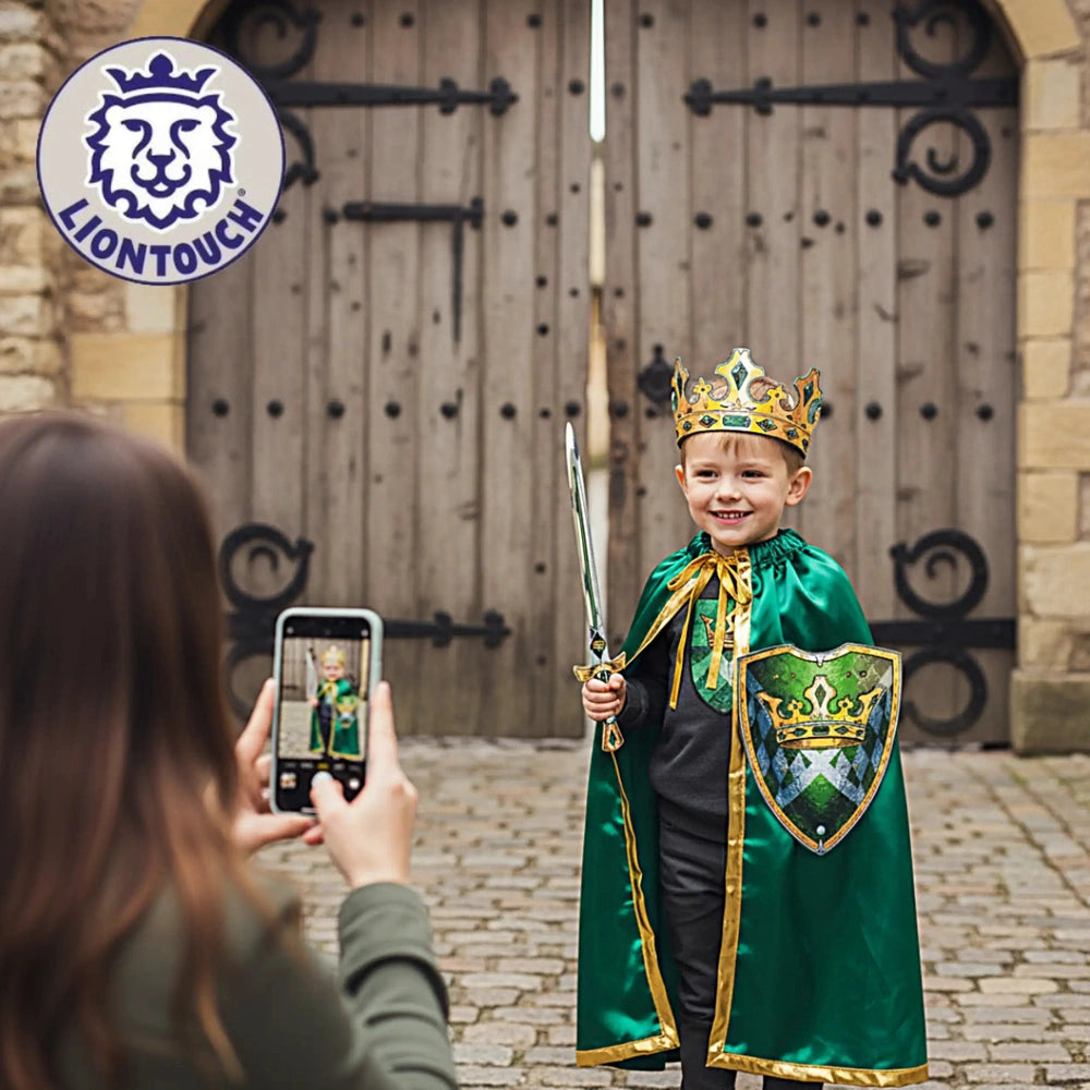 Liontouch Kingmaker Crown worn by a smiling child in a green robe, holding a sword and smartphone in front of a wooden door.