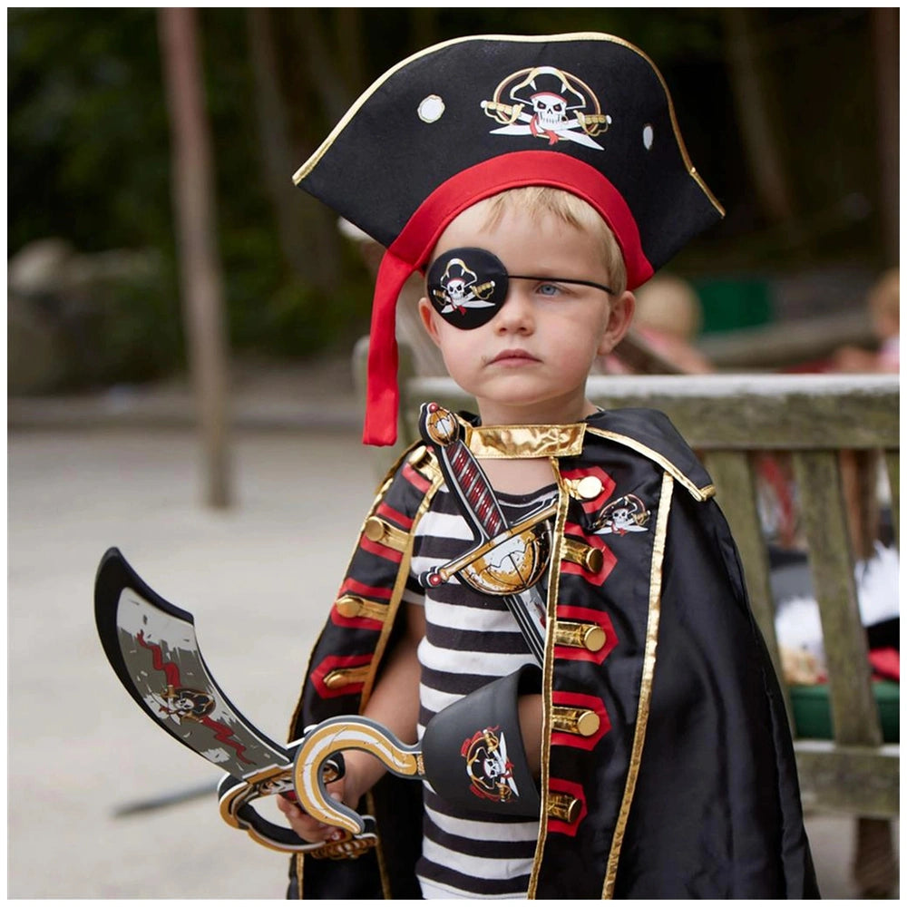 Child in pirate costume with a black hat, gold-trimmed cape, and toy sword in an outdoor setting.