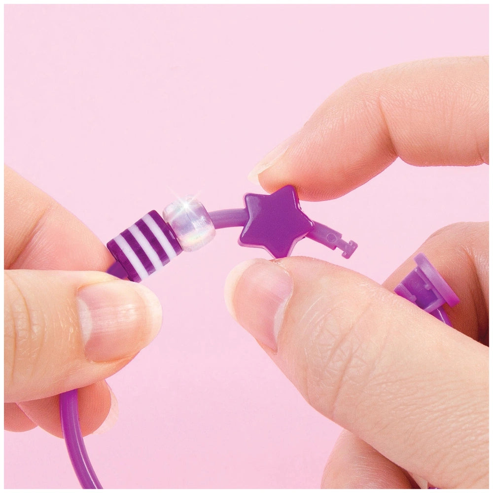 Purple DIY fashion beaded bangle bracelet with star and key shapes held between two fingers on a smooth surface.