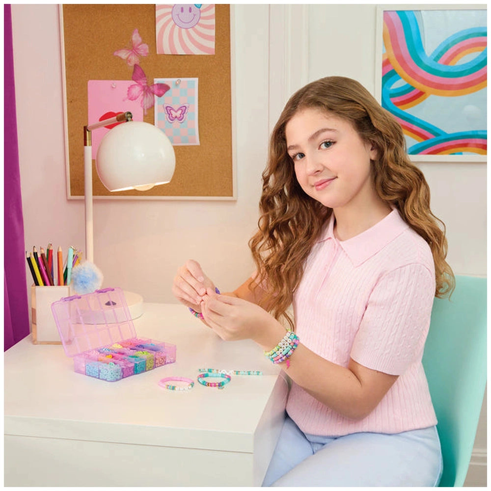 MAKE IT REAL Heishi Craze set showcased by a girl in a pink shirt, creating jewelry with colorful beads on a white desk.